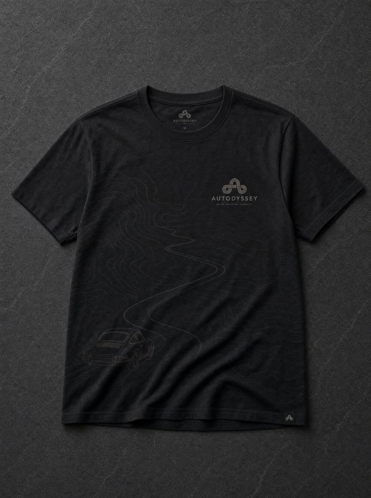 The charcoal Model Line tee laid flat, the road curving down toward the 911